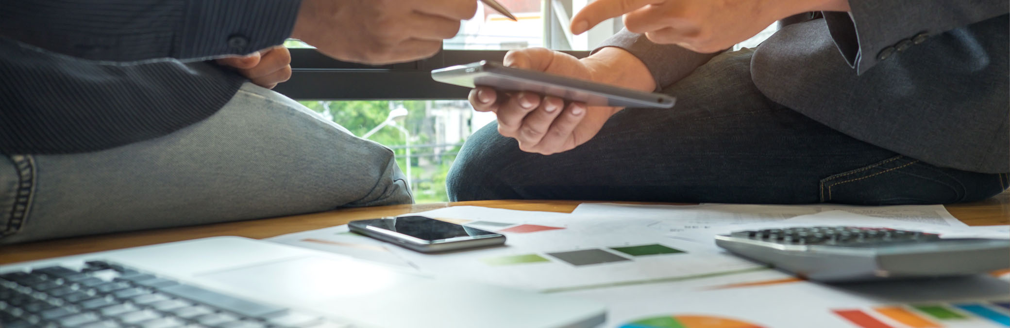 Business concepts,Two men are consulting a business,Two men pointing at a tablet, laptop , graphs , calculator and smart phone on the desk.